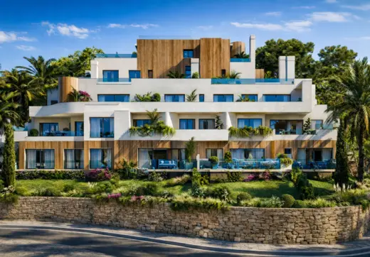 Modern residential building at Royal River Marbella with white facade, wood accents, large terraces and tropical garden.